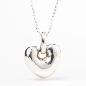 A handcrafted silver necklace hangs a smooth modern heart charm.
